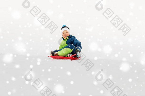 快乐的男孩在冬天乘雪橇滑下雪山