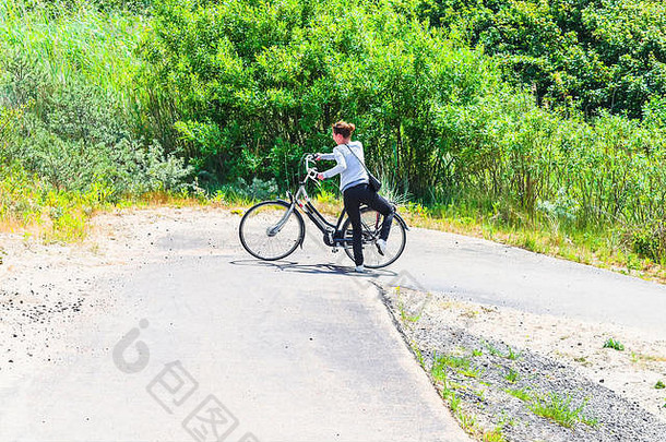 北海绿色沙丘景观中，一名骑着电动自行车的妇女。