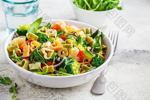 情人节食品概念。在一个白碗里放一份沙拉，里面有意大利心、橄榄、西红柿、菠菜和花椰菜。