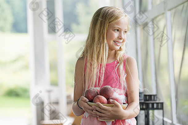 抱着一抱新鲜桃子的年轻女孩。