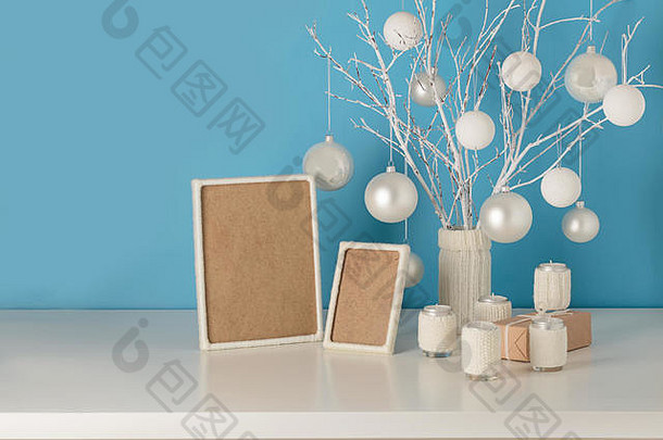 白色针织封面的花瓶，带有白色的树枝和圣诞玩具。带蜡烛的针织套烛台。用w装饰的空木架
