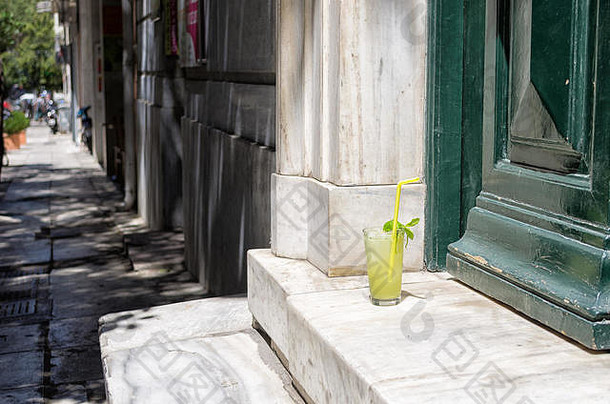 希腊雅典市中心一座老建筑入口处台阶上的一杯新鲜柠檬水