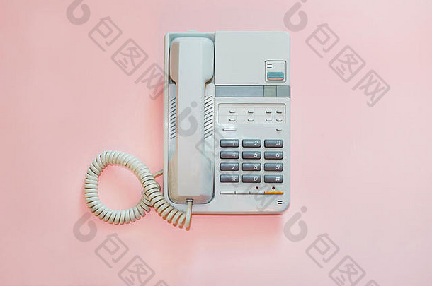 粉红色背景上的白色办公室电话。概念