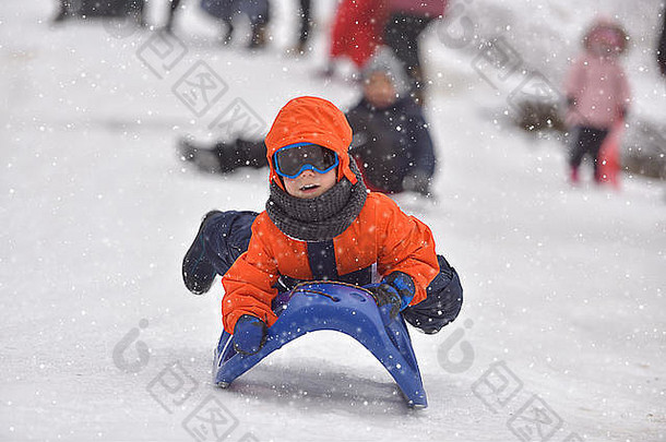 冬天，小男孩骑在雪地滑梯上