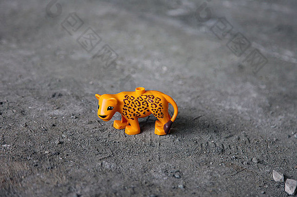 这是一张橙色玩具塑料老虎站在地板上的照片。这是一个孩子的小玩具雕像