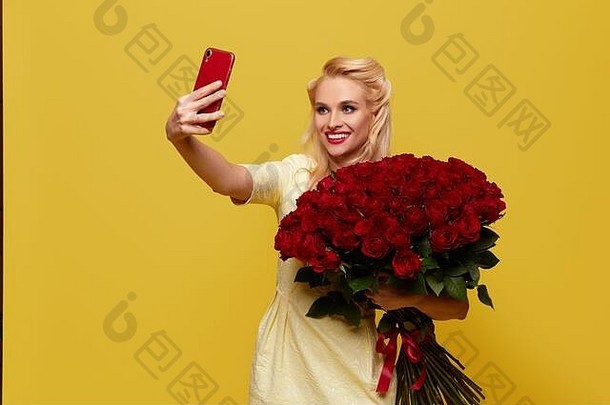 年轻的美女<strong>女人</strong>复古的衣服使自拍移动电话大花束红色的<strong>玫瑰</strong>明亮的黄色的背景礼物概念