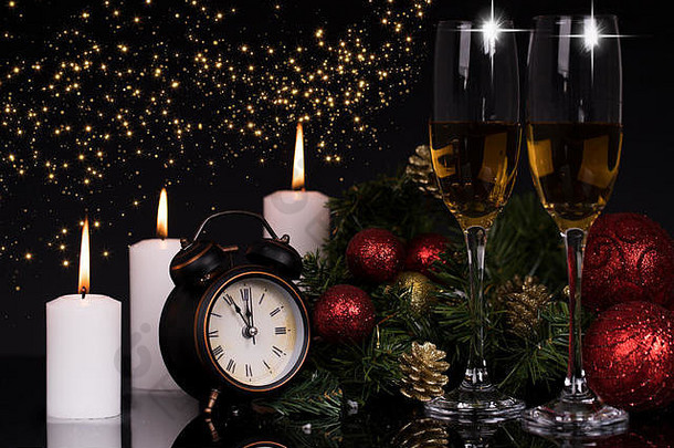 两个酒杯，香槟酒，蜡烛和圣诞装饰品，黑色背景，反光。空间。圣诞快乐，新年快乐