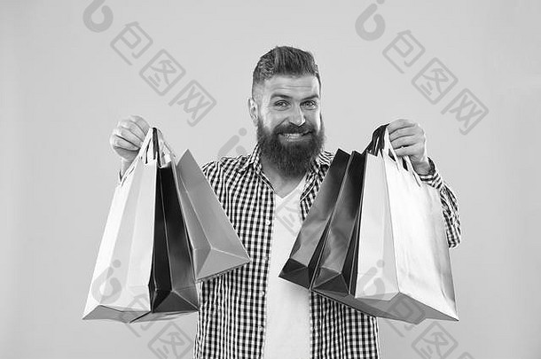 一个留着大胡子的时髦男人，一张欢快的脸，背着黄色背景的纸袋。享受黑色星期五的购物优<strong>惠</strong>。购物打折享受购物。让购物更快乐。