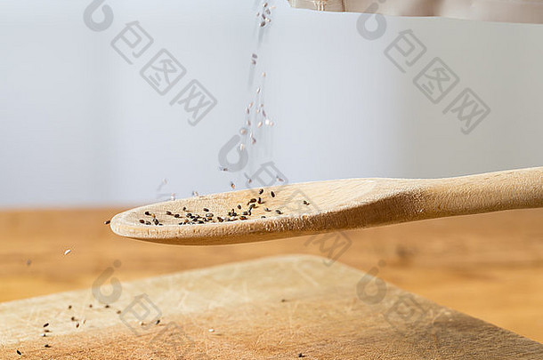 被称为黑甲种子的超级食物被倒入厨房桌子上木面包板上方的木背勺中