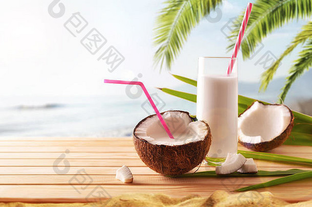 椰子汁水果和玻璃放在背景为海滩的木桌上。替代牛奶概念。前视图。水平构图。