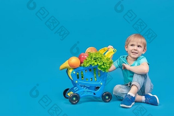 孩子欧洲外观金发碧眼的男孩坐着地板上购物电车超市填满食品杂货水果面包