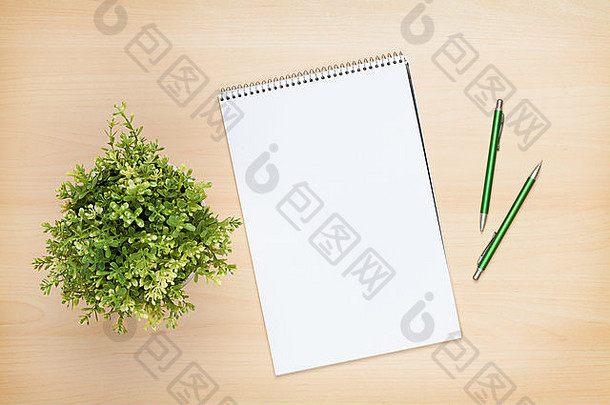 木桌上的空白记事本、钢笔和花。俯瞰