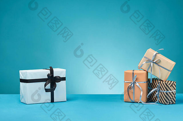 不同尺寸、颜色、条纹和普通纸礼品盒，在蓝色表面和背景上系上丝带和蝴蝶结。特写，空间。