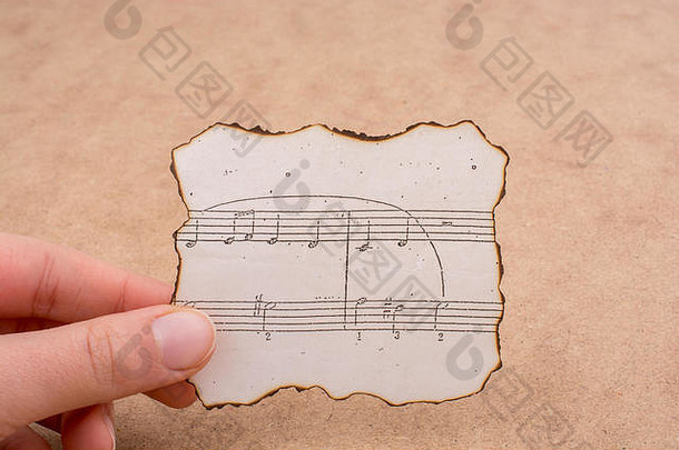手拿着一张烧焦的纸，上面写着音乐