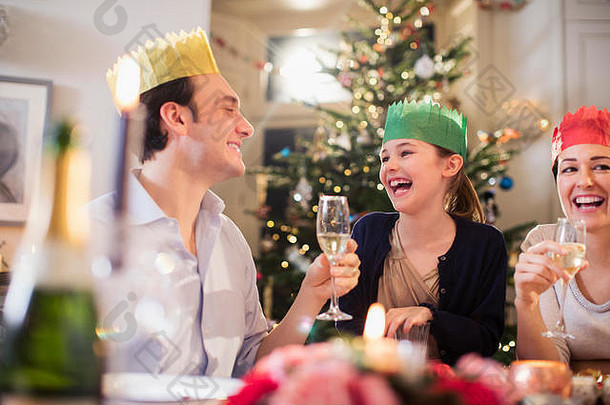 快乐家庭纸冠享受圣诞节晚餐喝香槟笑