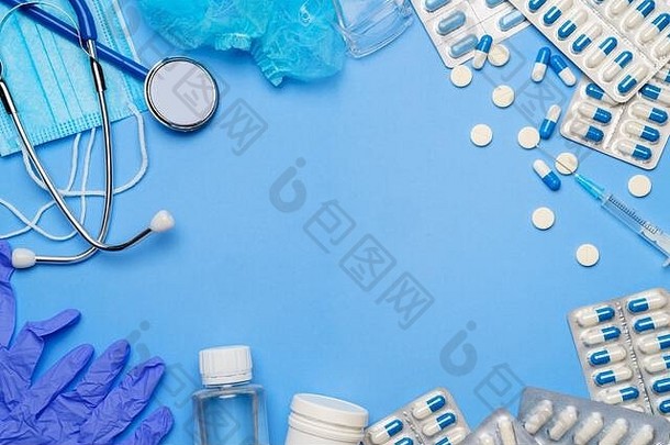 冠状病毒防护概念-听诊器、防护面罩、药丸、蓝色背景的注射器。