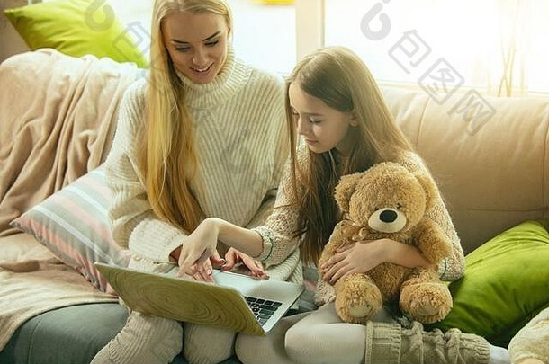 心在<strong>温暖</strong>。幸福的家庭。母亲和女儿一起在家度过时光。看电影，使用笔记本电脑，大笑。童年、节日、<strong>母亲节</strong>。