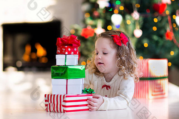 圣诞节早晨，一家人在壁炉旁。孩子们打开圣诞礼物。孩子们在圣诞树下拿着礼物盒。