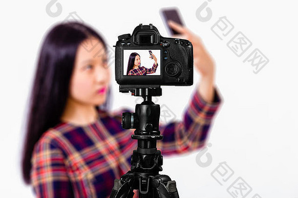 聚焦于三脚架上摄像机的实时画面，少女在背景模糊的背景下在后屏幕上拍摄自拍图像。青少年维洛格生活