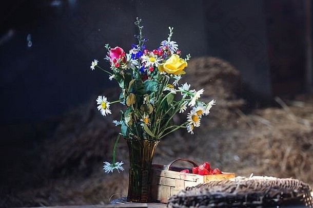 花瓶里的花和桌子上的草莓，光线充足，气氛优美