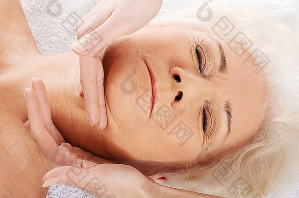 一位老妇人正在做一个面部按摩。水疗概念。白色的。