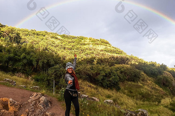 遵循你<strong>梦</strong>想的概念。一个女人走在通往山的小路上，指着天空中的彩虹。