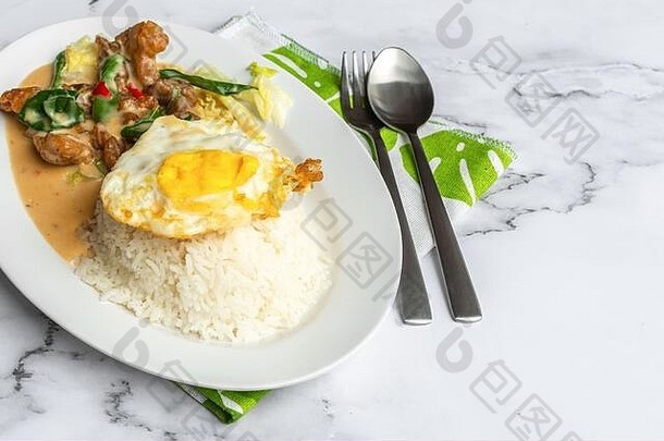 奶油咸蛋鸡配米饭和鸡蛋。桌上有亚洲食物。