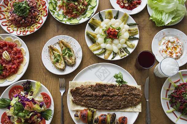 阿达纳烤肉串；木制餐桌上健康新鲜的沙拉品种和开胃菜