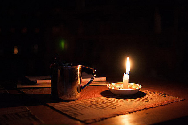 黑暗中木桌上的杯子和蜡烛。尼泊尔洛奇内部酒店