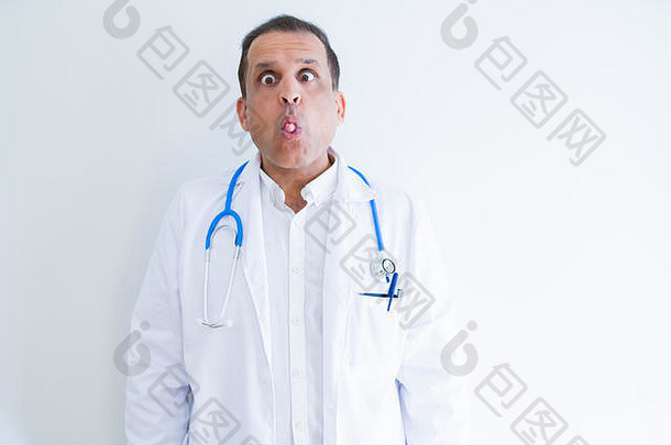 中年医生男子在白色背景上戴着听诊器和医用外套，用嘴唇<strong>做鱼</strong>脸，疯狂而滑稽的姿势。滑稽表情
