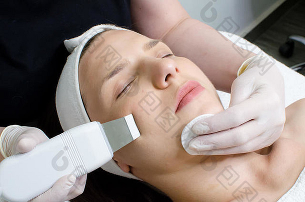 美貌女子接受超声波面部去角质美容院的超声波面部清洁程序。现代超声波皮肤设备