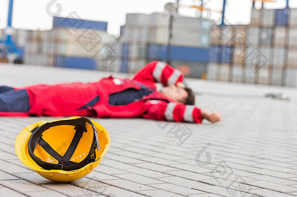 船厂戴着黄色安全帽，沮丧的男工人躺在船厂里