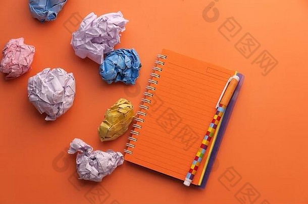皱巴巴的纸球和记事本颜色背景。