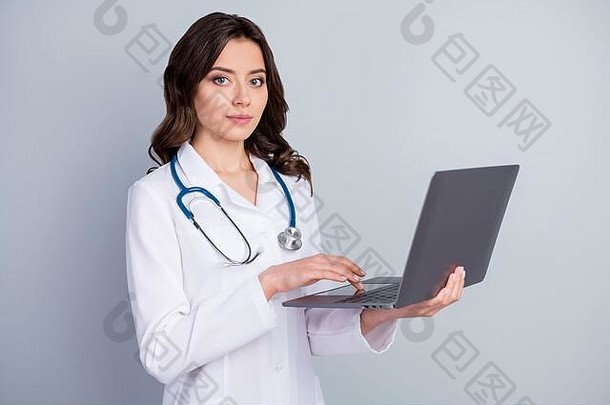 经验丰富的感染2019冠状病毒疾病患者使用笔记本电脑准备COVID-19肺炎治疗穿白色的外套，隔离灰色