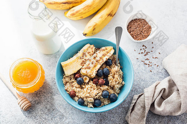 燕麦片粥香蕉蓝莓坚果蜂蜜蓝色的碗表格前视图概念清洁吃重量损失节食健康的Lifest