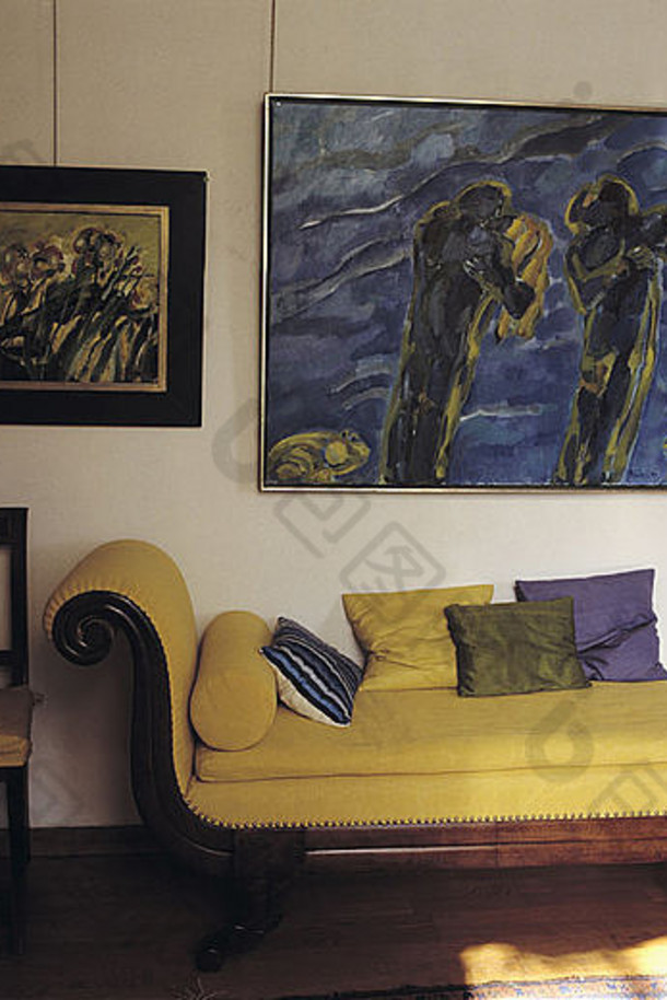联排别墅客厅古董黄色躺椅上方的大型现代绘画