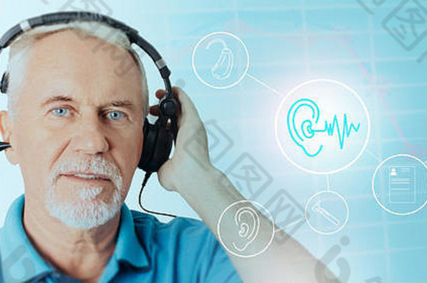 戴着耳机的老年患者在全息<strong>交互式</strong>医疗图标附近接受听力测试。听力考试的未来技术