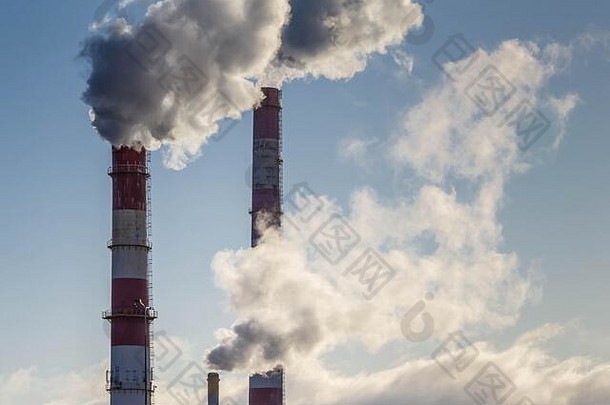 蓝色天空背景上带有烟雾的工厂管道。工业烟囱向蓝天排放浓烟。空气污染。全球生态问题。