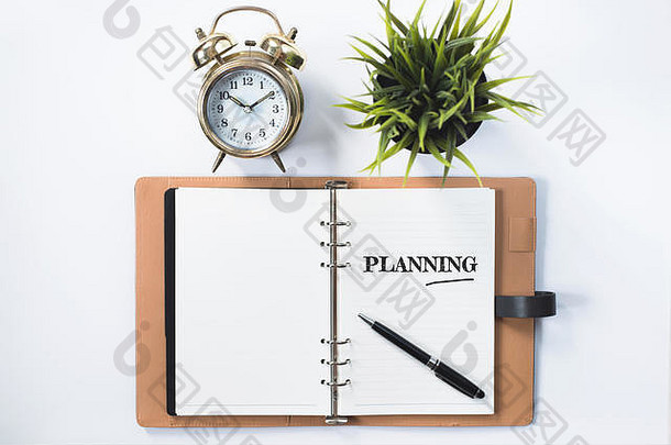 时钟、绿色植物和空白笔记本，带有计划文字。规划理念