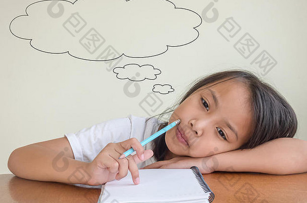 亚洲小女孩坐在木桌上用铅笔写字