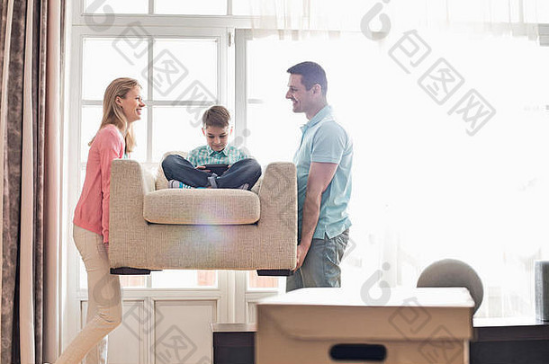 幸福的父母抱着儿子坐在新家的扶手椅上