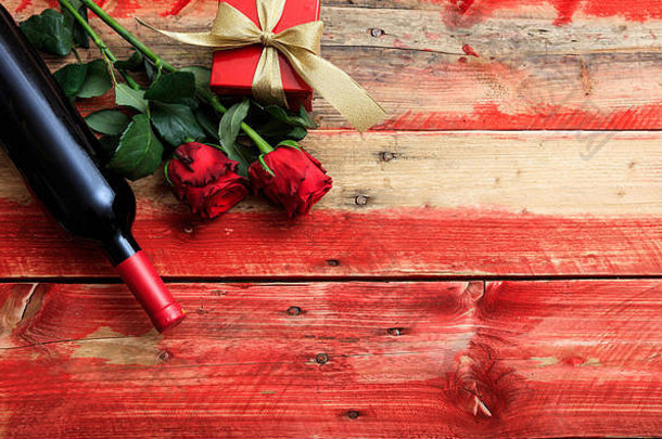 情人节的概念。木制背景上的红酒瓶、玫瑰和礼物