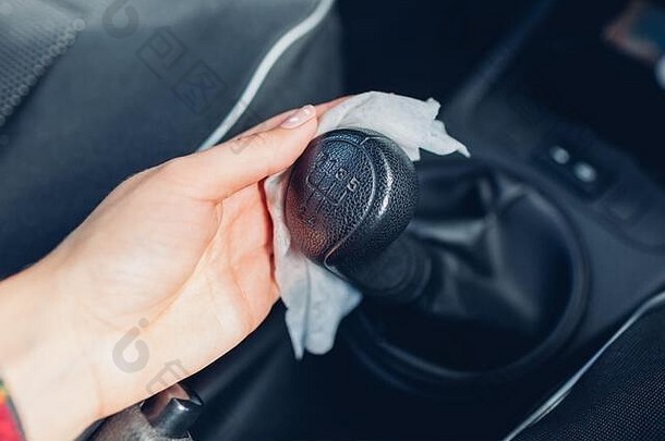 冠状病毒汽车消毒。驾驶员用含酒精的抗菌湿巾清洁变速器。新冠肺炎大流行