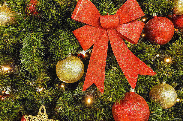 美丽的圣诞装饰作为背景-特写中圣诞树上的灯光、红结和装饰品的照明