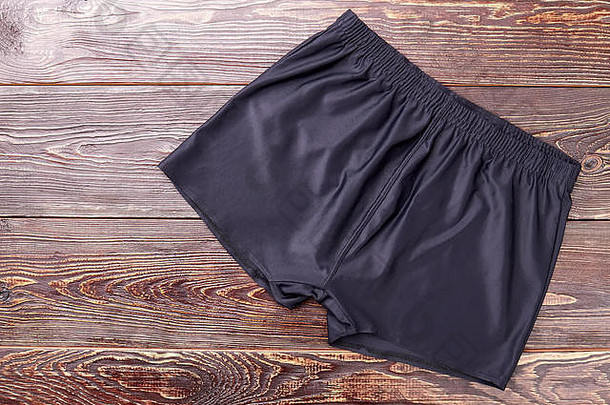 黑色跑步短裤，木质背景。