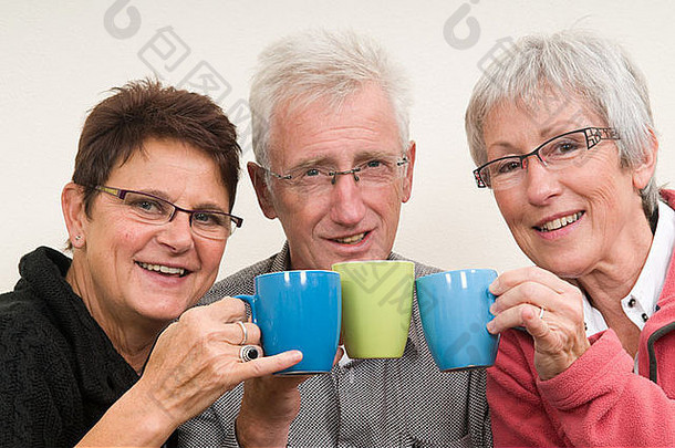 三个老人拿着一杯咖啡。