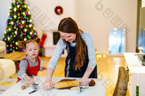 圣诞前夜，一家母女在家烤饼干。装饰精美的房间、壁炉、圣诞树和背景灯。