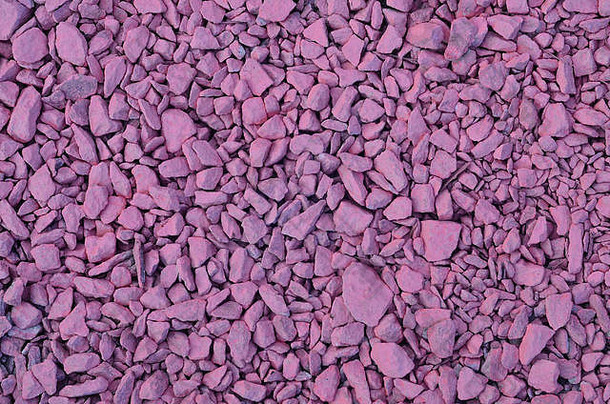 纹理来自一堆碎石，涂成浅粉色。许多不同形状和大小的粉红色石头的背景图像