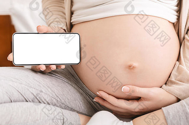 孕妇在她的大肚子附近拿着手机