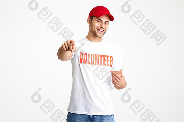 一个快乐的男人的肖像，穿着志愿者t恤衫，用两个手指分别指着白色背景